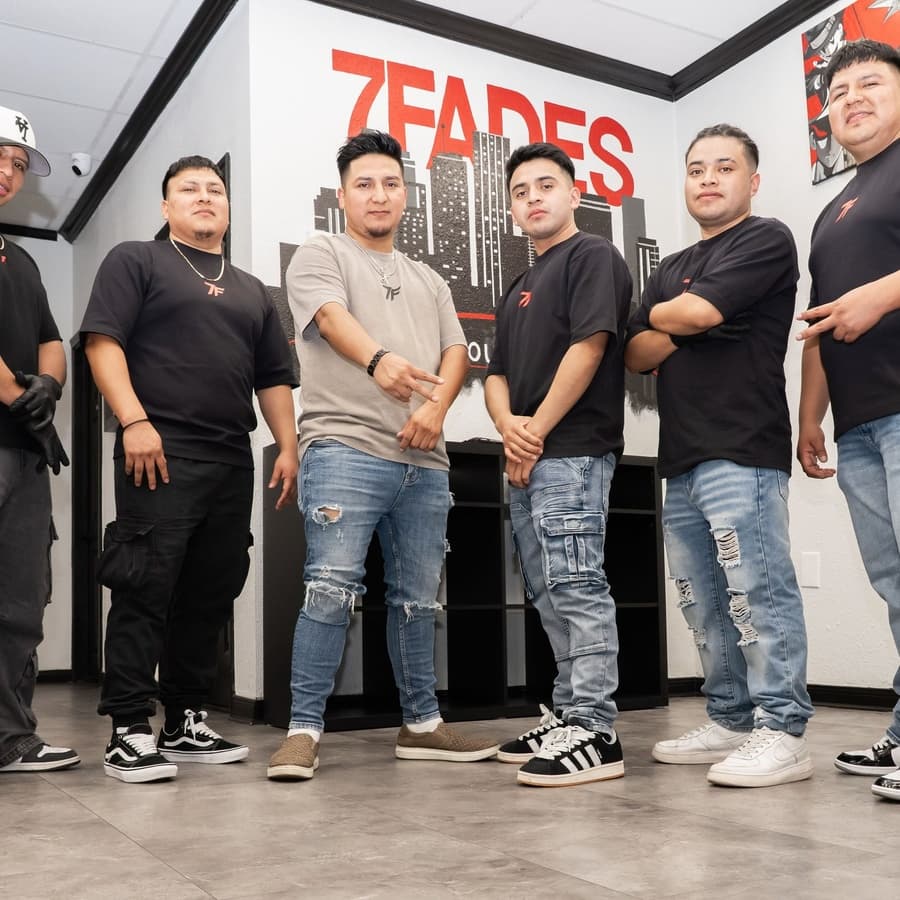 The 7Fades barbershop team in front of the Houston skyline mural